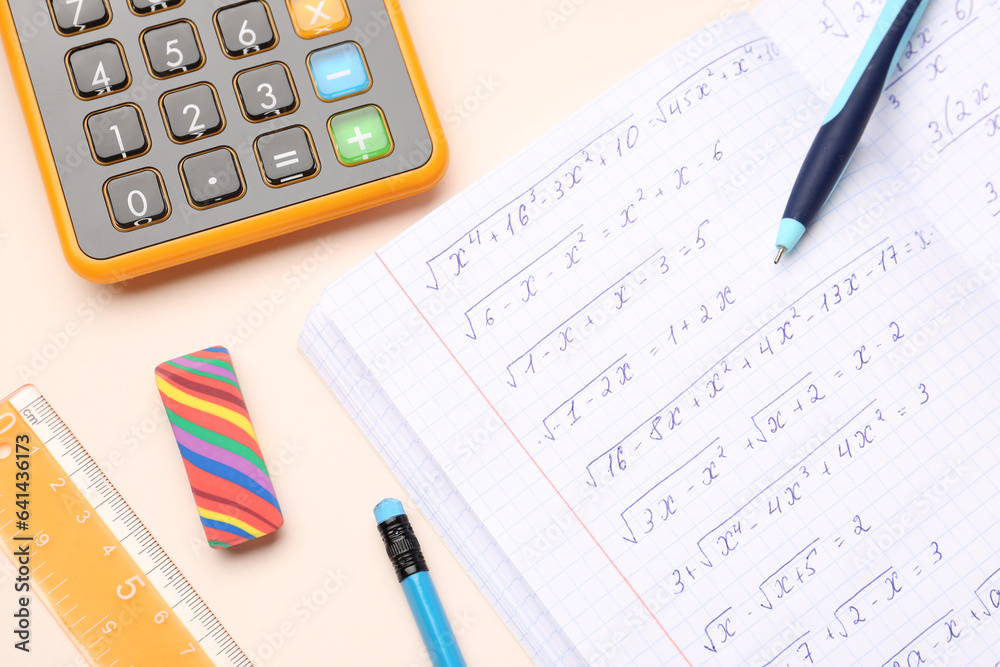 Copybook with maths formulas, calculator and stationery on beige background Copybook with maths formulas, calculator and stationery on beige background