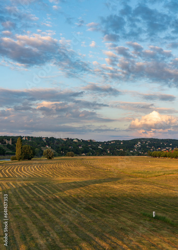 Valley near the river Elbe in Dresden, Germany. Mowed meadow at sunset. Beautiful clouds in the sunset sky