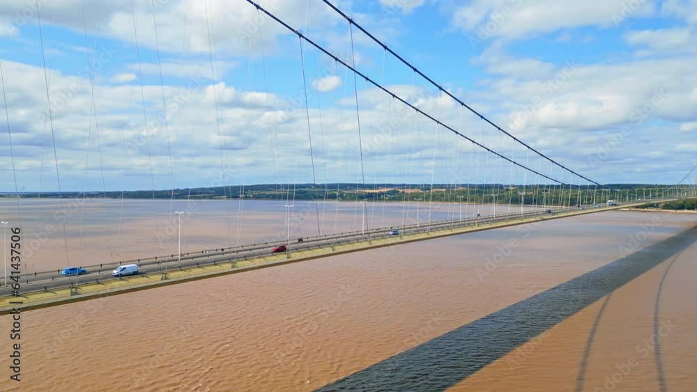 Aerial drone view of Humber Bridge, 12th largest suspension span, gracefully crossing River Humber, connecting Lincolnshire to Humberside with traffic. Aerial drone view of Humber Bridge, 12th largest suspension span, gracefully crossing River Humber, connecting Lincolnshire to Humberside with traffic.