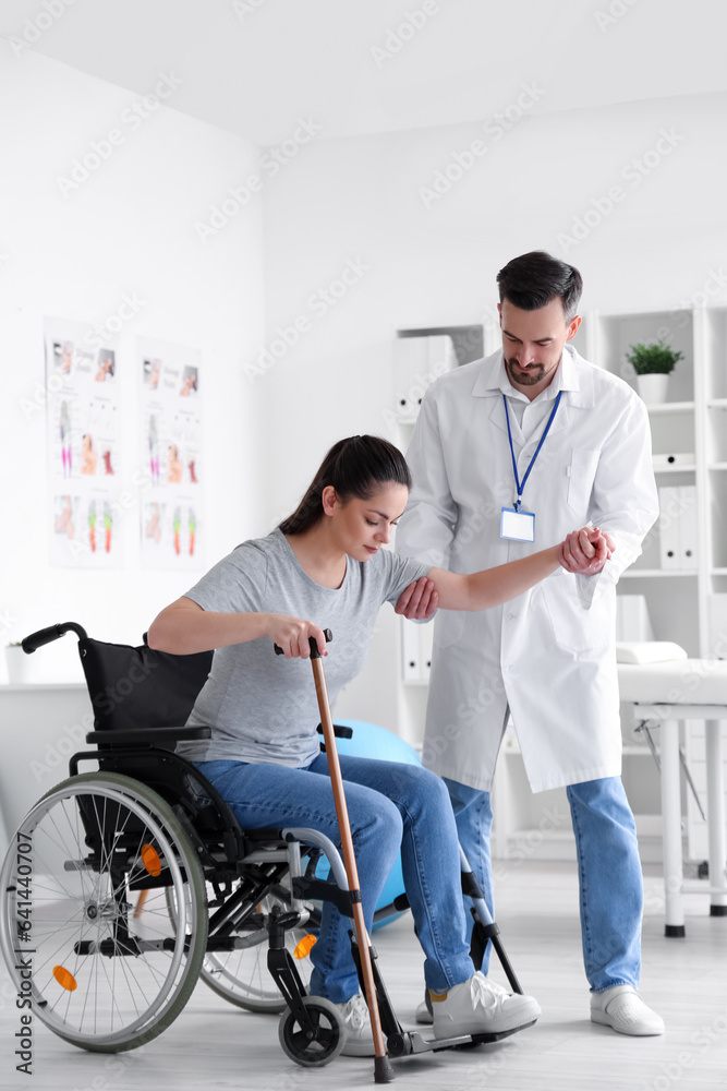 Male physiotherapist helping young woman to stand up in rehabilitation center Male physiotherapist helping young woman to stand up in rehabilitation center