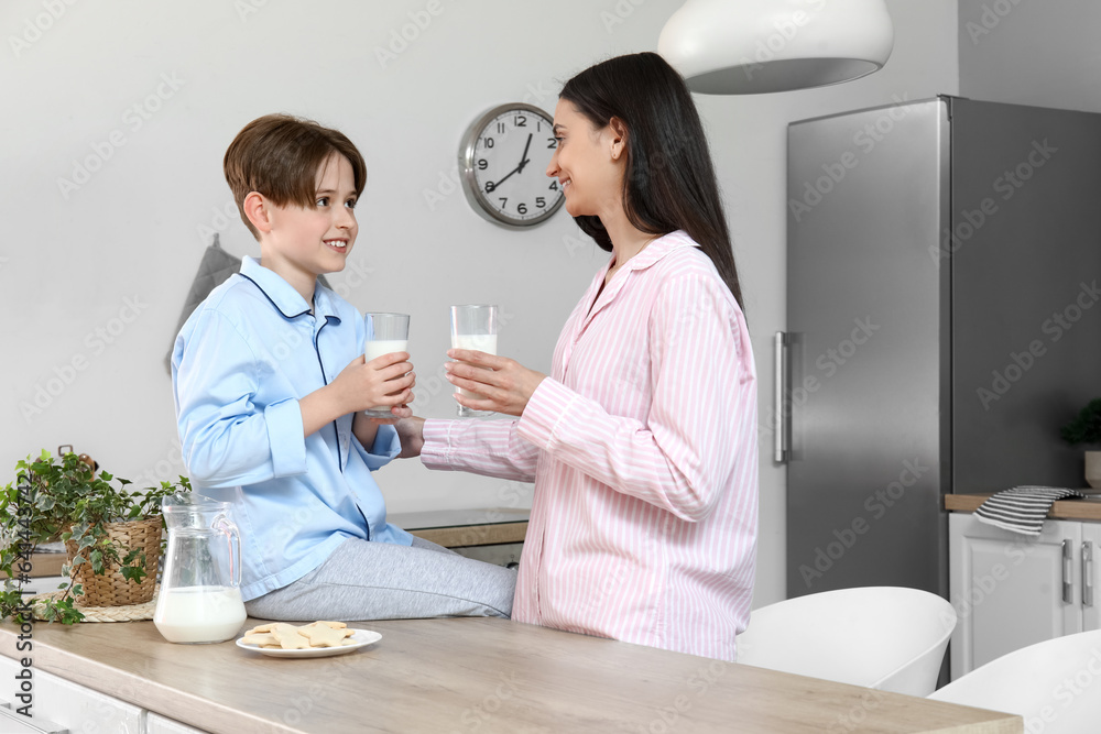 Fototapeta premium Little boy and his mother with cookies and fresh milk in kitchen