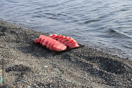 Watermelon, strawberries and raspberries on the sand by the sea