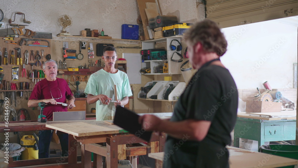 Small Business owner checking with employees online orders holding tablet device inside carpentry workshop. Staff working woodwork job occupation Small Business owner checking with employees online orders holding tablet device inside carpentry workshop. Staff working woodwork job occupation