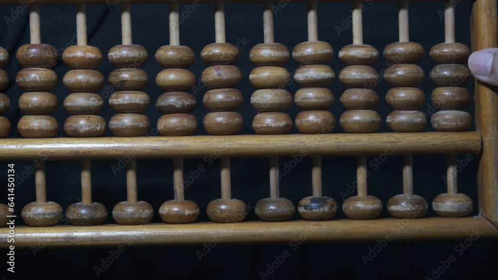 abacus. sempoa. Made of wood. Flipping over a wooden abacus with black background. 4K footage. Seeds following in the same direction, together and simultaneously. abacus. sempoa. Made of wood. Flipping over a wooden abacus with black background. 4K footage. Seeds following in the same direction, together and simultaneously.