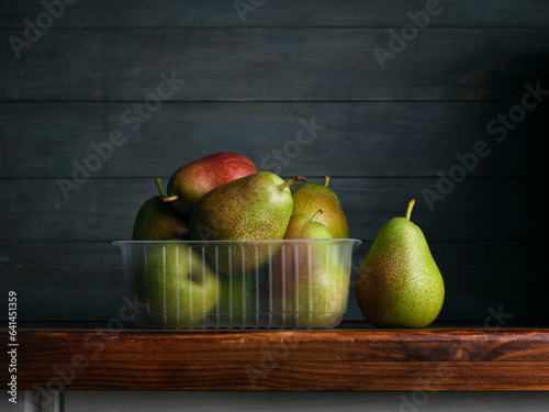 Image of Still Life with stack of green Pears. Dark wood background, antique wooden table.