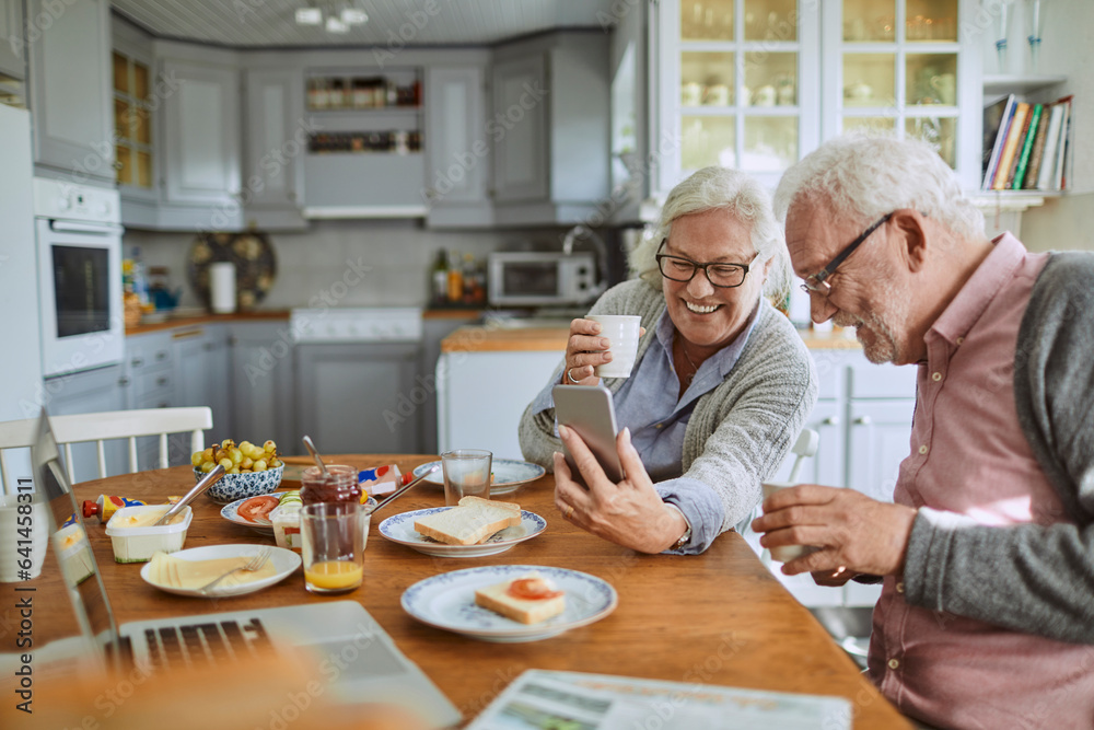 Senior couple using a smartphone and having breakfast in the morning in the kitchen Senior couple using a smartphone and having breakfast in the morning in the kitchen