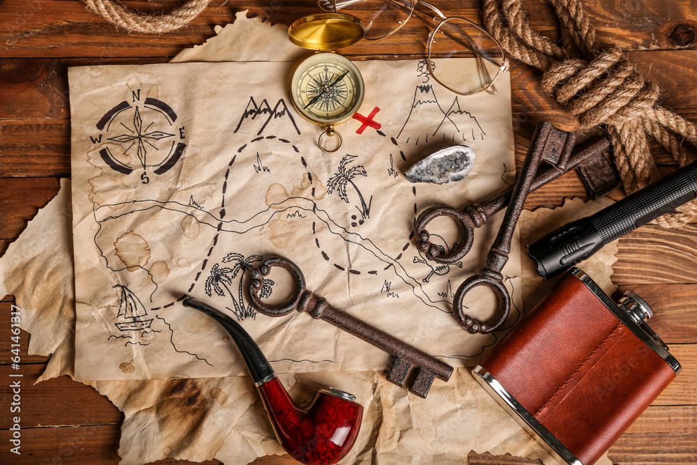 Treasure map with travel equipment, hip flask and smoking pipe on brown wooden background