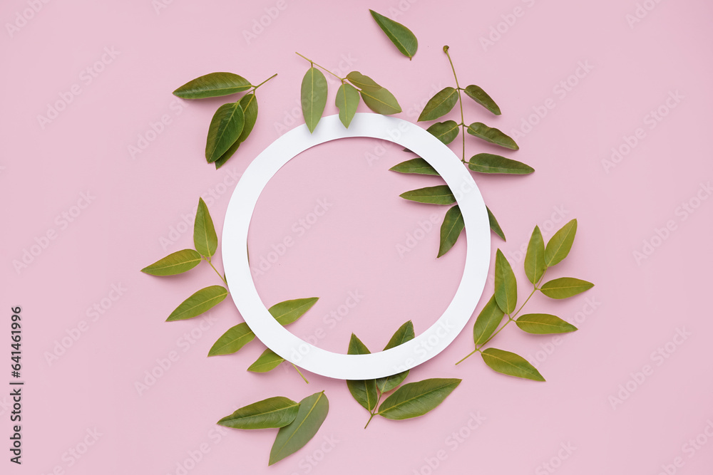 Composition with green leaves and paper circle frame on pink background Composition with green leaves and paper circle frame on pink background