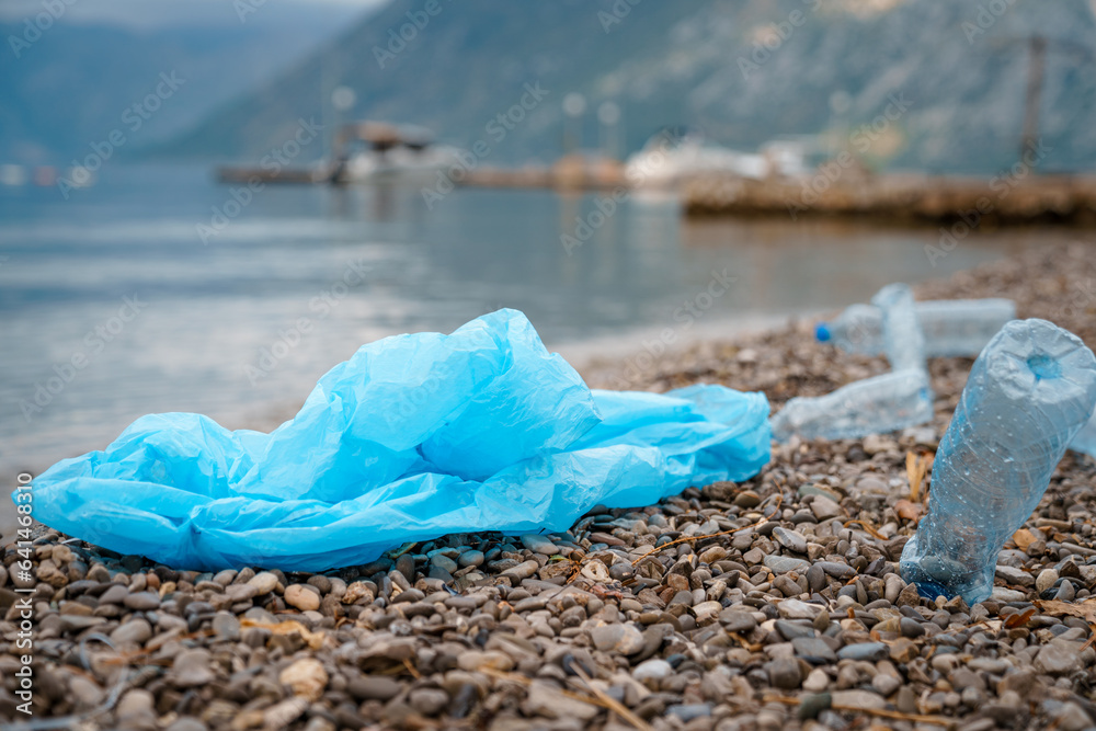 Photo of plastic bag and bottles lying on seacoast. Photo of plastic bag and bottles lying on seacoast.