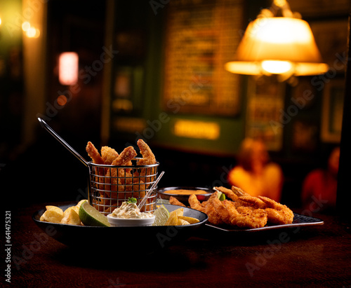two servings of seafood prawns appetizer with french fries restaurant blurred background