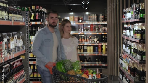 Couple walk through the alcohol section of hypermarket photo