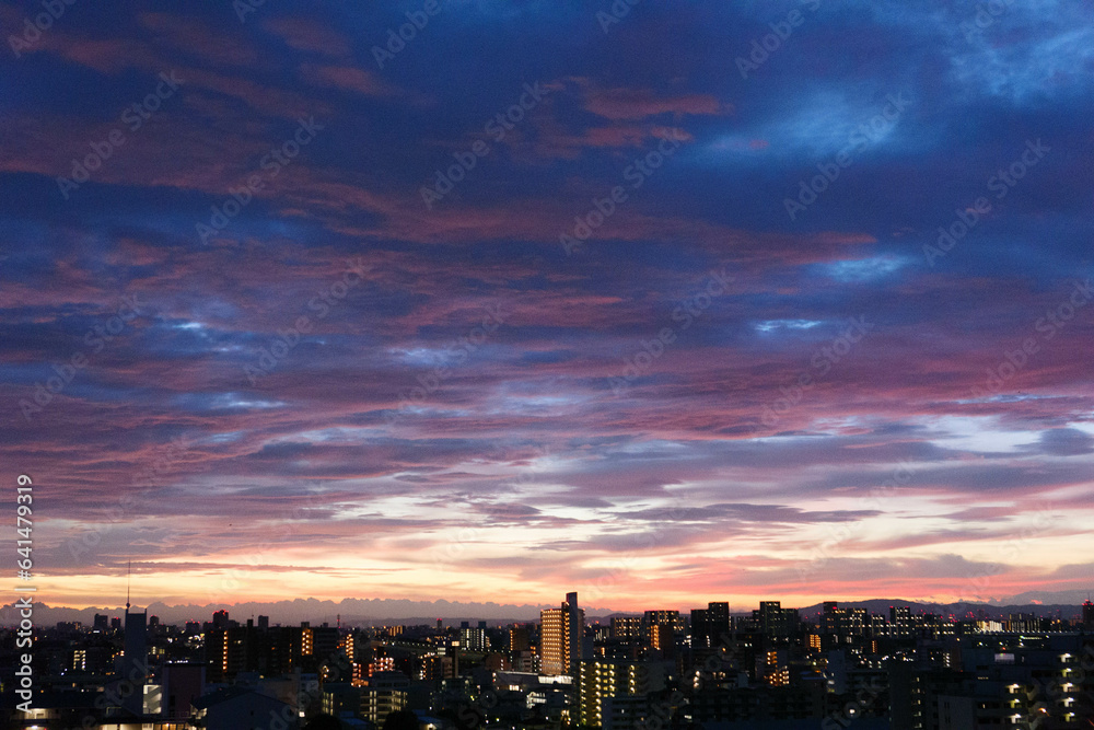 都市の夜明け。東の空が明るくなり雲がまだ昇る前の太陽に照らせら美しいグラデーションを見せる。神戸市内から大阪方面を臨む