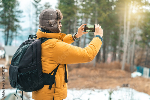 Cheerful well dressed hiker using mobile phone in the mountains. Ambitious young male blogger taking photos for his new travel project.
