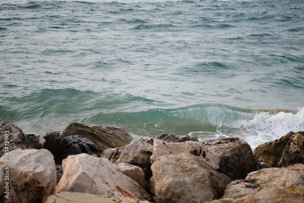 The waves of the Mediterranean Sea crash against boulders along the shoreline of Tel Aviv, near Jaffa.