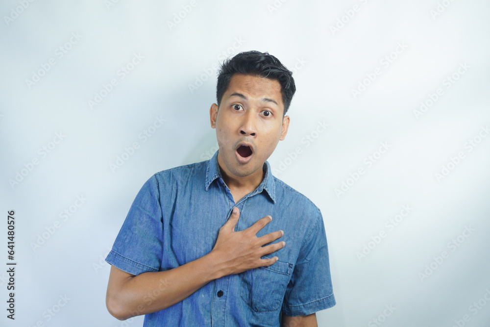 Portrait of young asian man wearing blue shirt shocked to open mouth in front of white background Portrait of young asian man wearing blue shirt shocked to open mouth in front of white background
