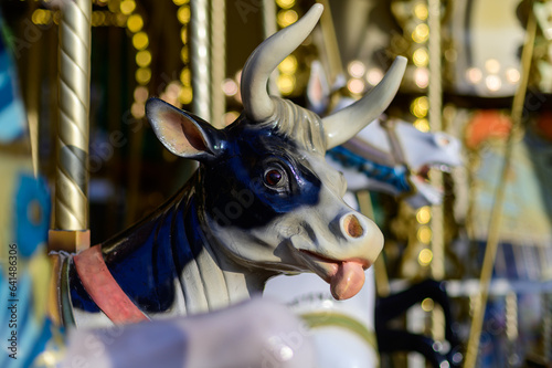 Colorful cow on traditional old french caroussel in city park in sunny day photo