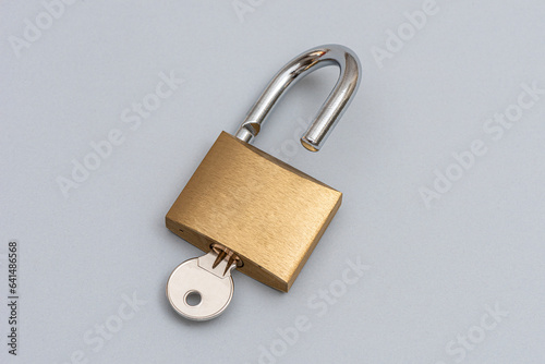 Unlocked golden padlock on the gray background.