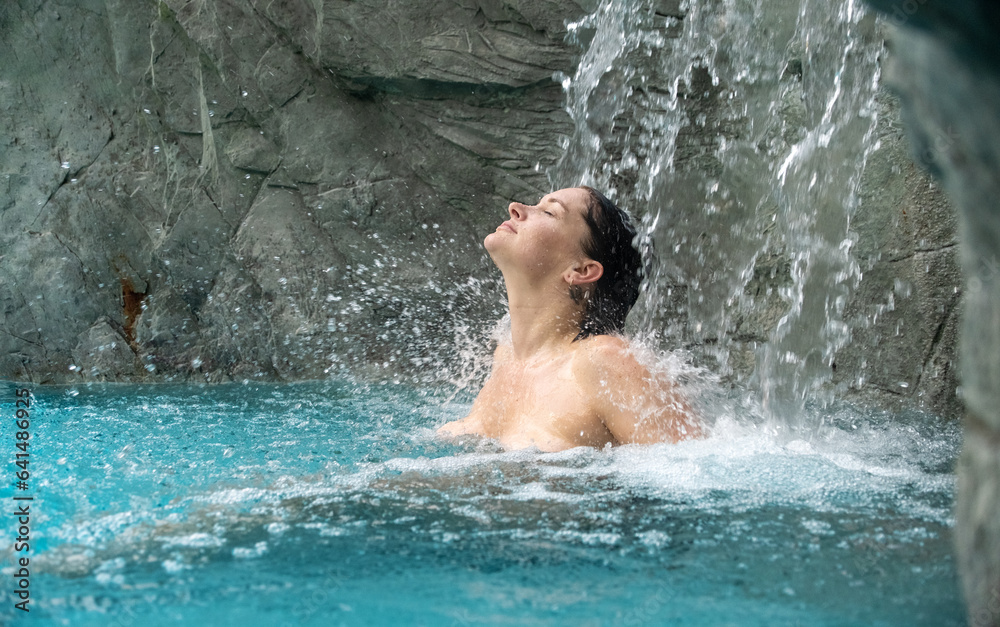 portrait of beautiful young sexy brunette naked woman, under the rippling splashing refreshing water of the waterfall in the Spa Wellness pool