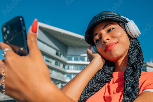 south american latin girl with mobile phone and headphones outdoors © carballo