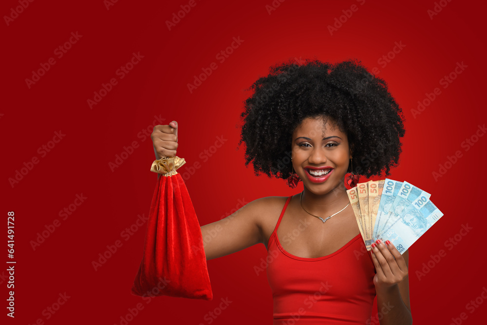a woman holds shopping bags and Brazilian money, a teenage girl smiles and looks at the camera, wearing a red dress against a red background a woman holds shopping bags and Brazilian money, a teenage girl smiles and looks at the camera, wearing a red dress against a red background