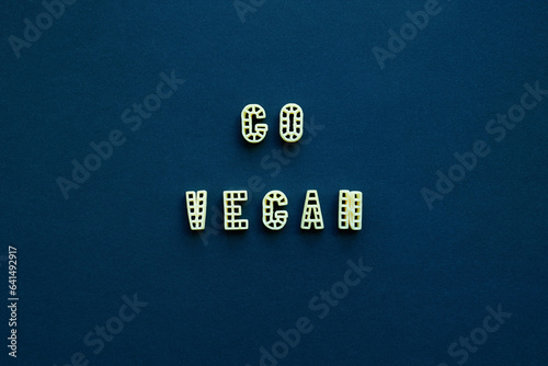 Close-up view of ‘Go vegan’ slogan made up of alphabet pasta against dark blue background   photo