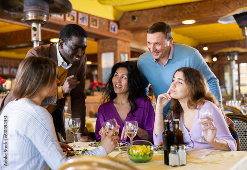 Smiling men invite women to dine for their table in the restaurant