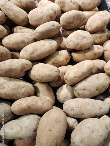 Potatoes pilled high at farmers market with artificial lighting. Fresh russet potatoes.