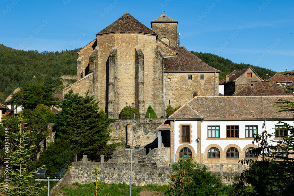 Townscape of Anso located in province of Huesca, Aragon, Spain, overlooking residential buildings and Romanesque medieval parish church of Saint Peter on sunny summer day surrounded by green Pyrenees
