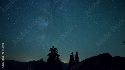 Zeitrafferaufnahme vom Sternenhimmel mit der Milchstraße in den Chiemgauer Alpen mit Wald und dem Rauschberg rechts, Bayern, Deutschland