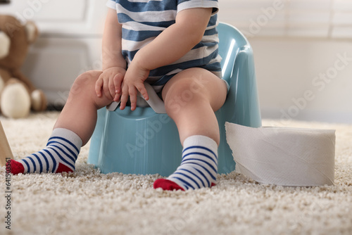 Cuadro en lienzo Little child sitting on plastic baby potty indoors, closeup