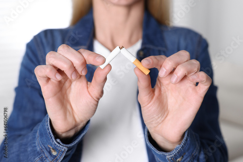 Woman breaking cigarette on light background, selective focus. Quitting smoking concept © New Africa