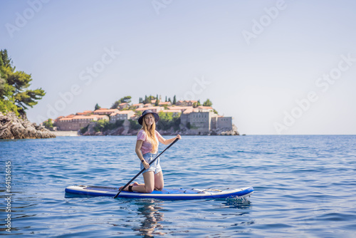 Young women Having Fun Stand Up Paddling in blue water sea near st stefan island in Montenegro. SUP © galitskaya