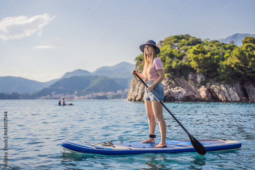 Young women Having Fun Stand Up Paddling in blue water sea near st stefan island against the backdrop of Milocer Park in Montenegro. SUP
