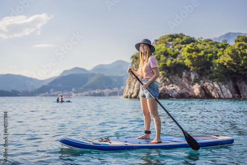 Young women Having Fun Stand Up Paddling in blue water sea near st stefan island against the backdrop of Milocer Park in Montenegro. SUP © galitskaya