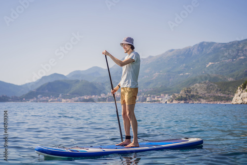 Young men Having Fun Stand Up Paddling in blue water sea near st stefan island against the backdrop of Milocer Park in Montenegro. SUP © galitskaya