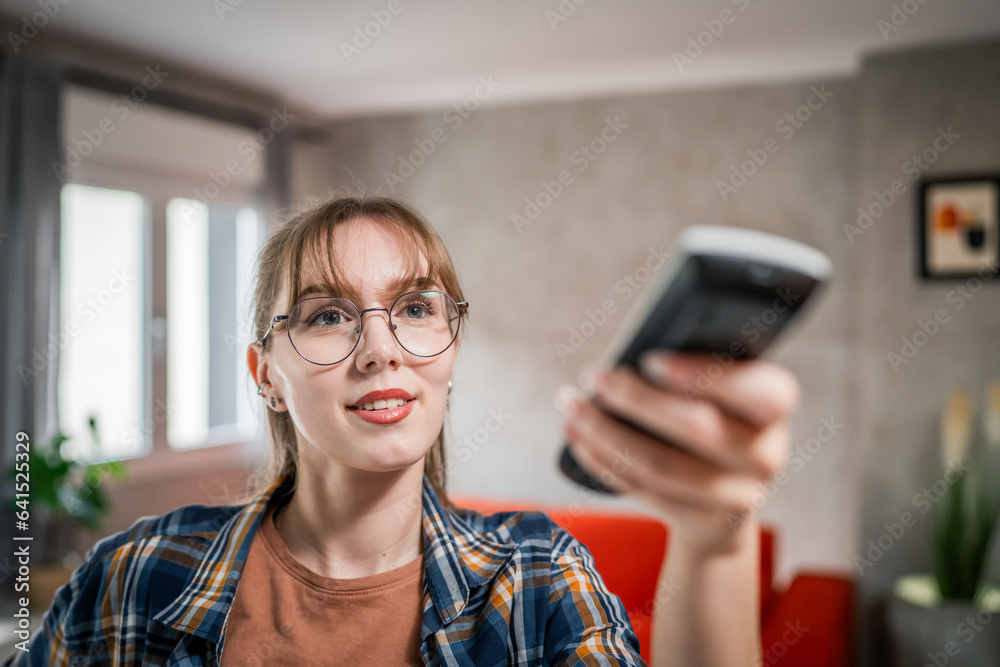 One young caucasian woman use remote control for TV or air-condition One young caucasian woman use remote control for TV or air-condition