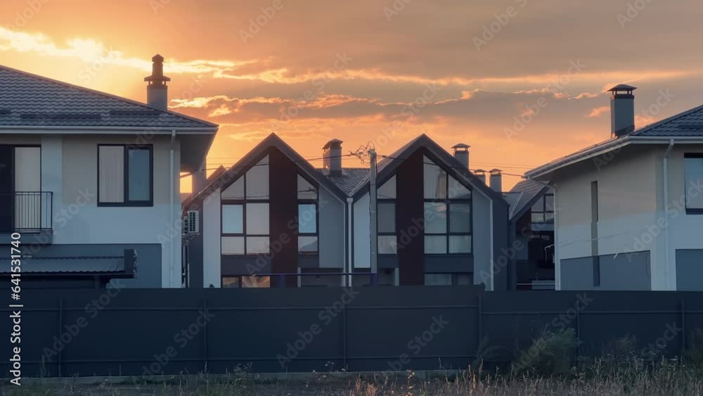 Newly built gated community with a group of homes and duplexes built together as a single development in suburbia at summer sunset Newly built gated community with a group of homes and duplexes built together as a single development in suburbia at summer sunset