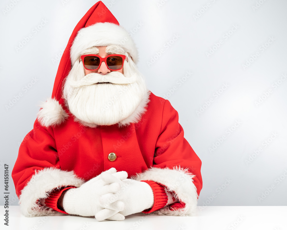 Portrait of santa claus sitting with his arms folded at a white table. Portrait of santa claus sitting with his arms folded at a white table.