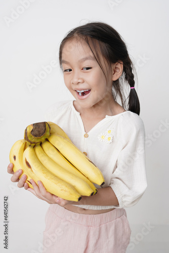 Girl is smiling with a golden banana in her hand, Shoot in a studio, white background.