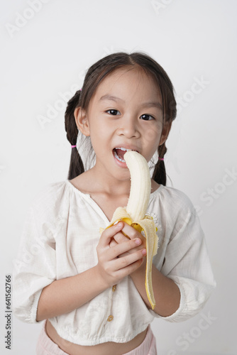Girl is smiling with a golden banana in her hand, Shoot in a studio, white background.