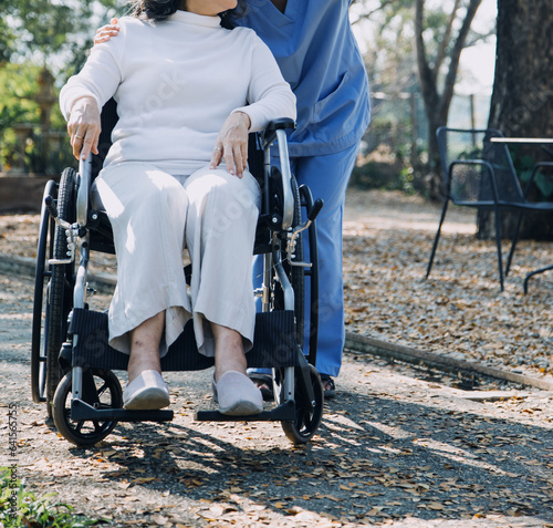 Asian young woman nurse at nursing home take care disabled senior man. Caregiver doctor serve physical therapy for older elderly patient to exercise and practice walking on walker or cane at backyard.