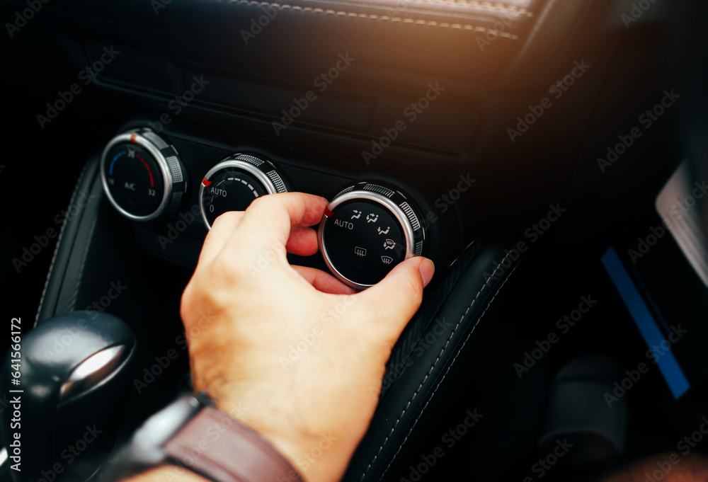 The driver hand adjusts the wind direction switch on a car air conditioning dashboard, turning button switch of a car air conditioning on a switch panel control, Car air condition technology concept.