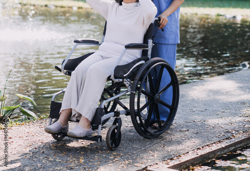 Asian young woman nurse at nursing home take care disabled senior man. Caregiver doctor serve physical therapy for older elderly patient to exercise and practice walking on walker or cane at backyard.