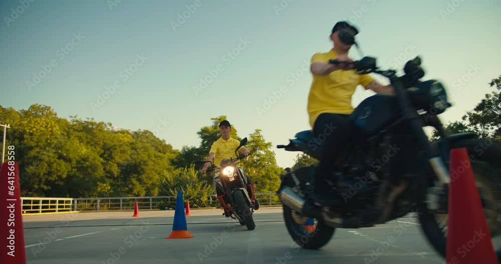 Two motorcyclists go to different sides at the training ground in a motorcycle school Two motorcyclists go to different sides at the training ground in a motorcycle school