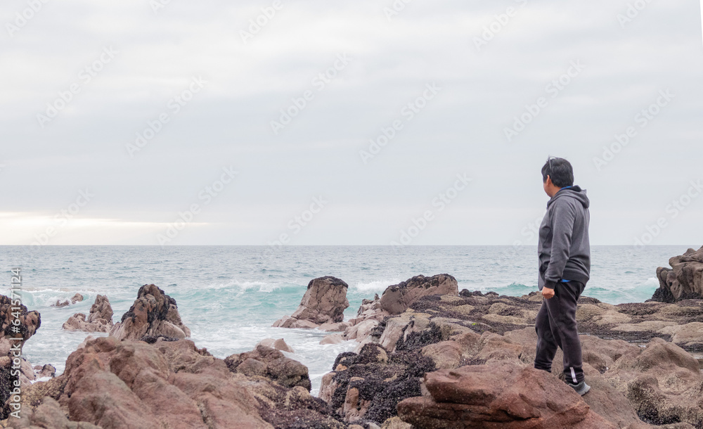 man looking at the sea from the rocks man looking at the sea from the rocks