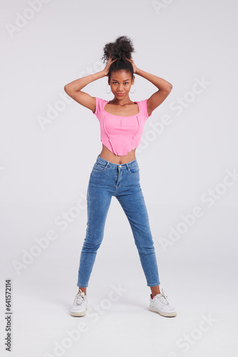 Effortlessly chic: Woman's studio pose captures her in a pink shirt and blue jeans, epitomizing modern style.