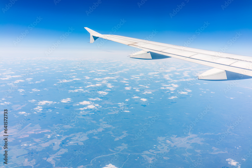 Fototapeta premium View from the airplane window at a beautiful cloudy sky and the airplane wing