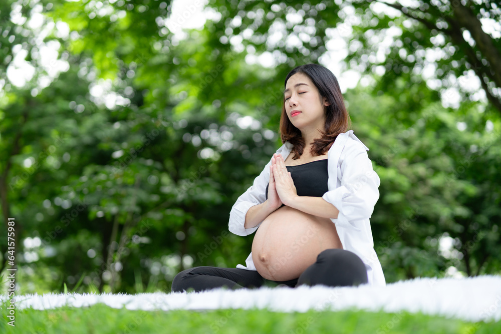 Portrait of Asian pregnant woman relaxing doing yoga in the park Portrait of Asian pregnant woman relaxing doing yoga in the park