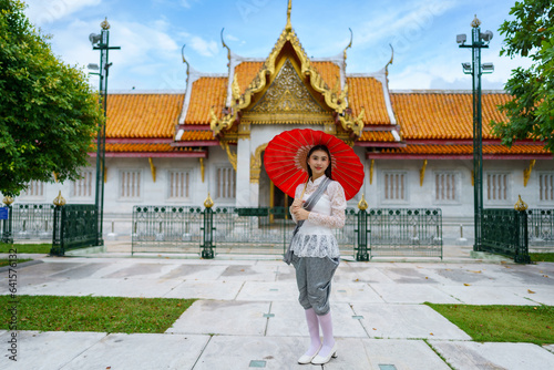 Portrait of beautiful young woman wearing Thai Rattanakosin national costume in a temple built according to Thai art in Thailand.