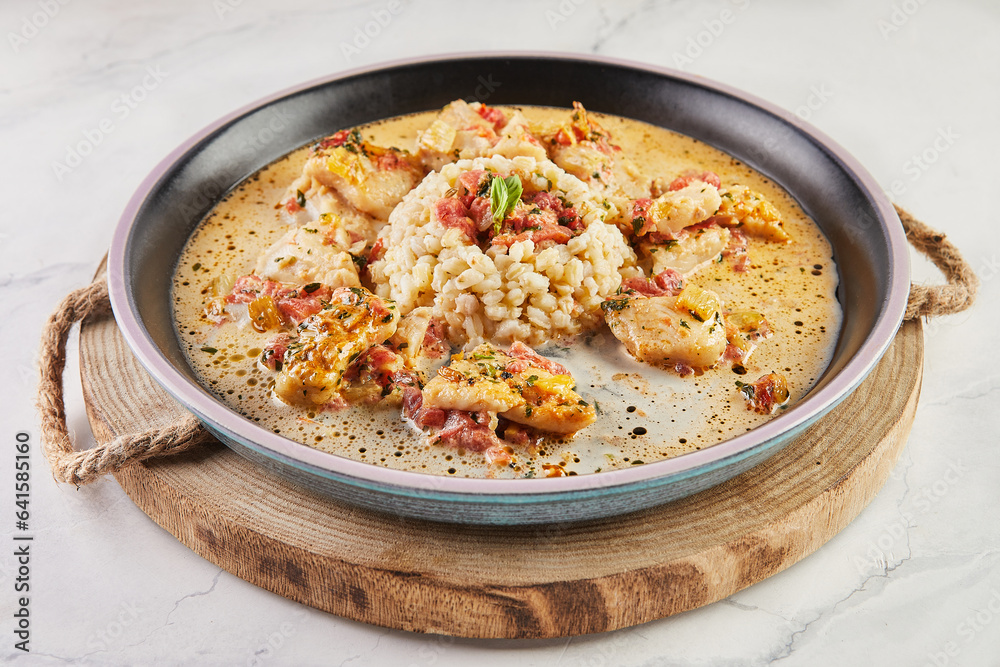 White fish fillet in wine sauce and millet porridge on plate on wooden board White fish fillet in wine sauce and millet porridge on plate on wooden board